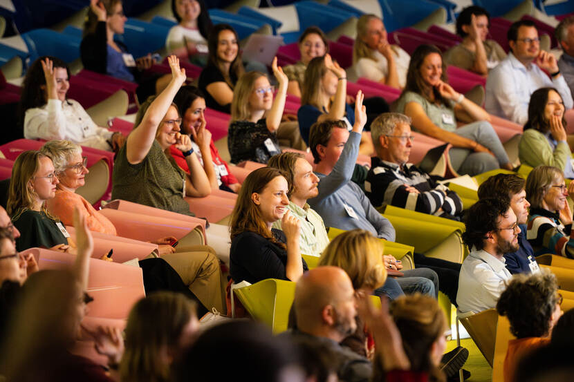 zaal met mensen die hun vinger opsteken